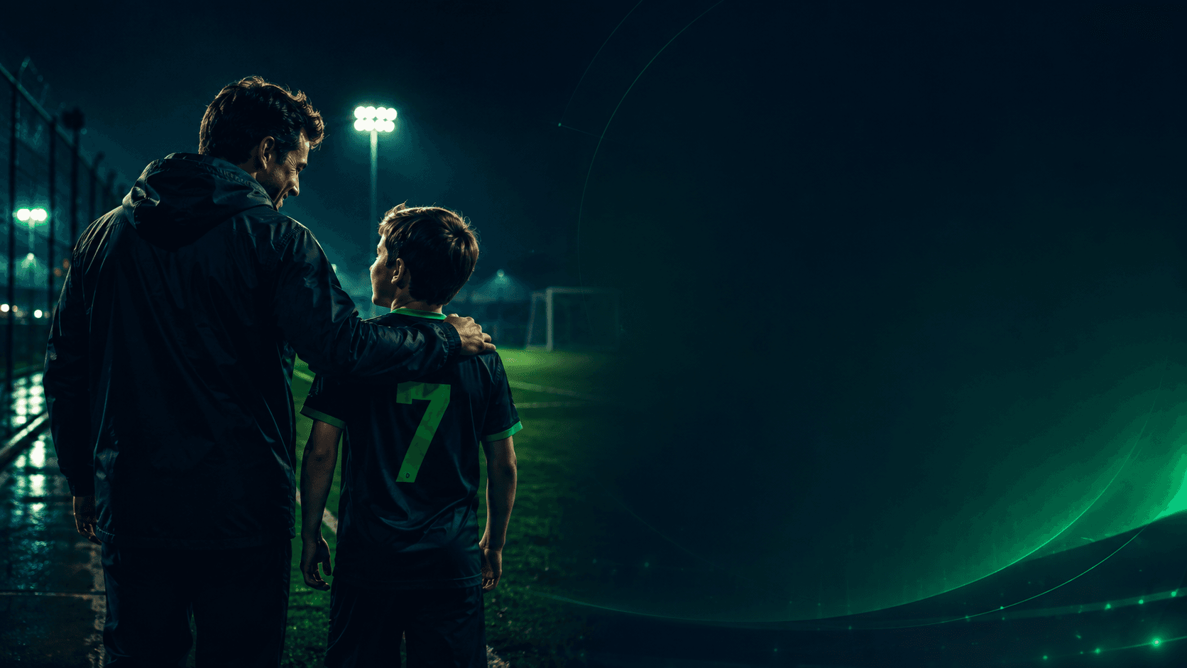Pai e filho de camisa 7 à beira do campo, à noite